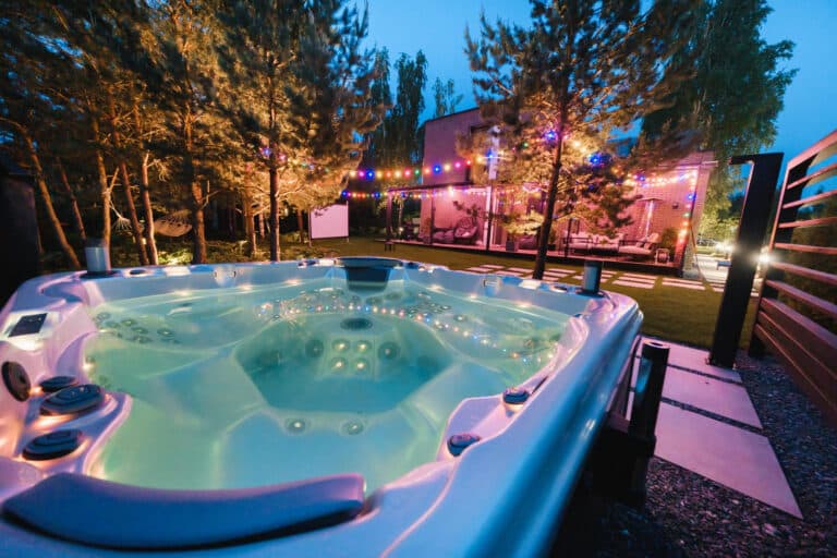 Jacuzzi éteint au fond d’un jardin lors d’une soirée d’été.